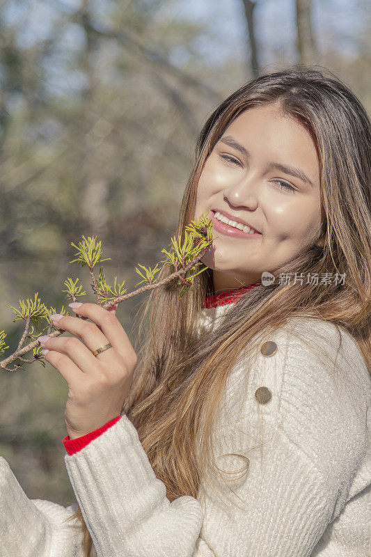 一个寒冷的感恩节/圣诞节秋天的早晨/下午，一位年轻的拉丁妇女在松冠森林中间休息时的画像。